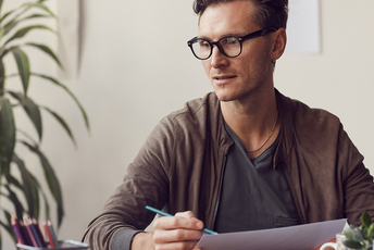 a decorative element: a young man wearing glasses sitting at a desk and working